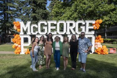 A group of individuals stand in front of a sign and pose for a photo.
